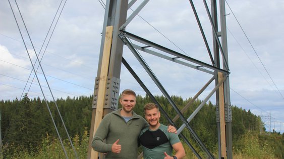 Die zwei Studierenden Luis und Adrian in Trondheim vor einem Strommast