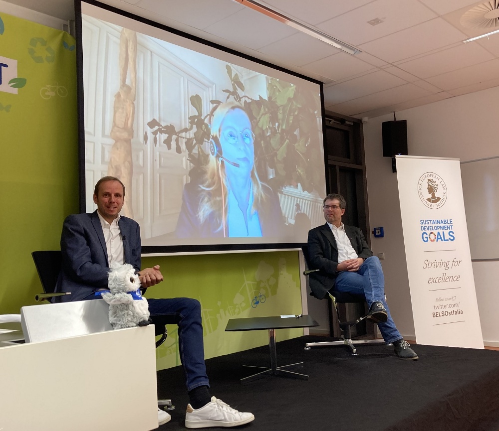 Nico Briskorn vom VfL Wolfsburg (links) und Prof. Dr. Litschen, Dekan der Fakultät Recht (rechts) auf dem Podium beim Forum Nachhaltigkeit. Auf der Leinwand im Hintergrund ist die zugeschaltete Dr. Irina Kummert zu sehen.