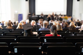 Abschlussfeier 2023: Person mit Graduation-Hut im Auditorium der Aula ist fokussiert (Foto: Judith Lübeß)