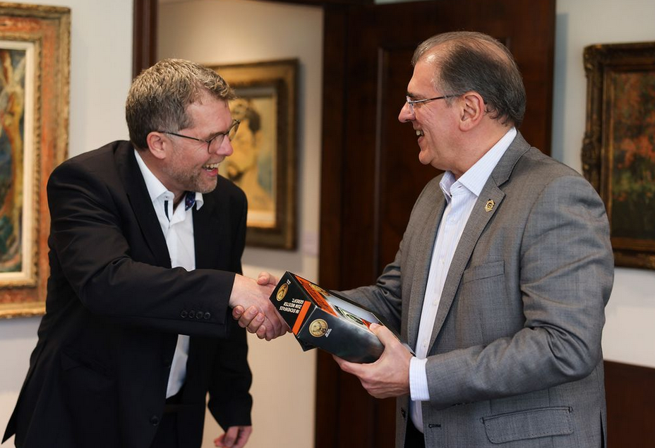 Prof. Dr. Litschen übergibt eine Flasche Jägermeister an den Rektor Dr. Randal Martins Pompeo