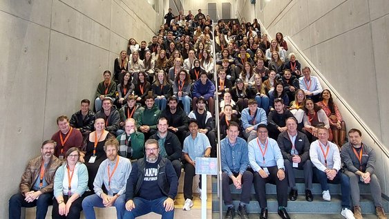 Studierende und Dozierende sitzen bei der 11. Internationalen Woche am Campus Wolfsburg auf einer Treppe.