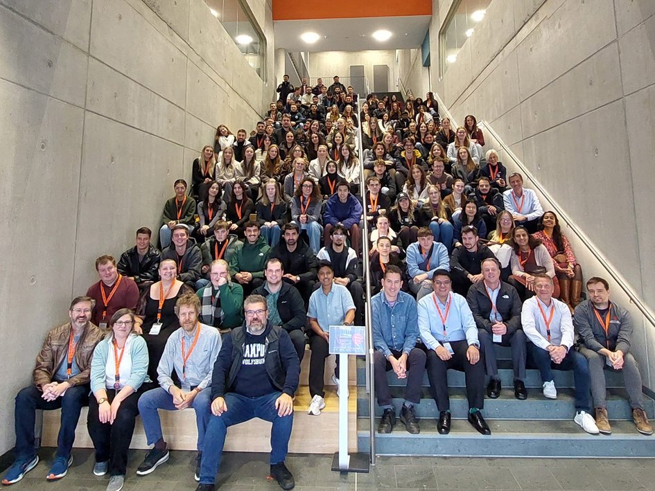 Studierende und Dozierende sitzen bei der 11. Internationalen Woche am Campus Wolfsburg auf einer Treppe.