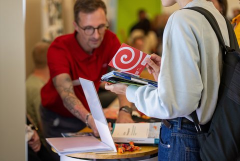Studierende mit Infomaterial in der Hand. (öffnet Vergrößerung des Bildes)
