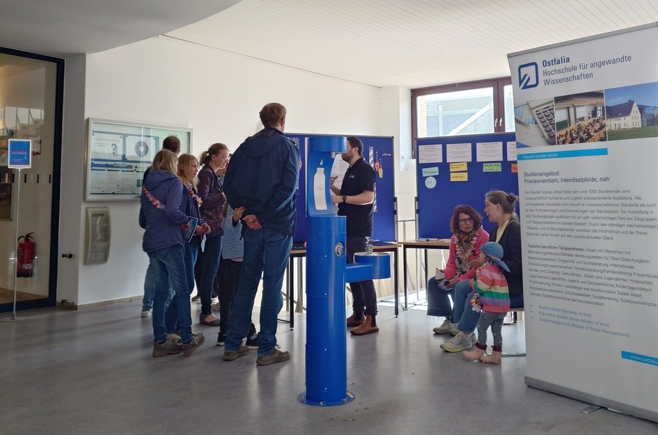 Besucher:innen stehen am Stand der Fakultät Soziale Arbeit und informieren sich über das Studienangebot.