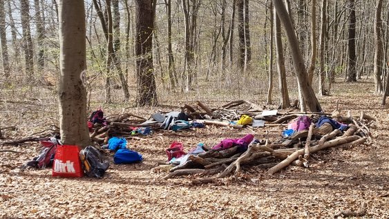 Waldsofa, das Kinder im Rahmen der Waldferienwoche aus großen Ästen gebaut haben mit Rucksäcken.