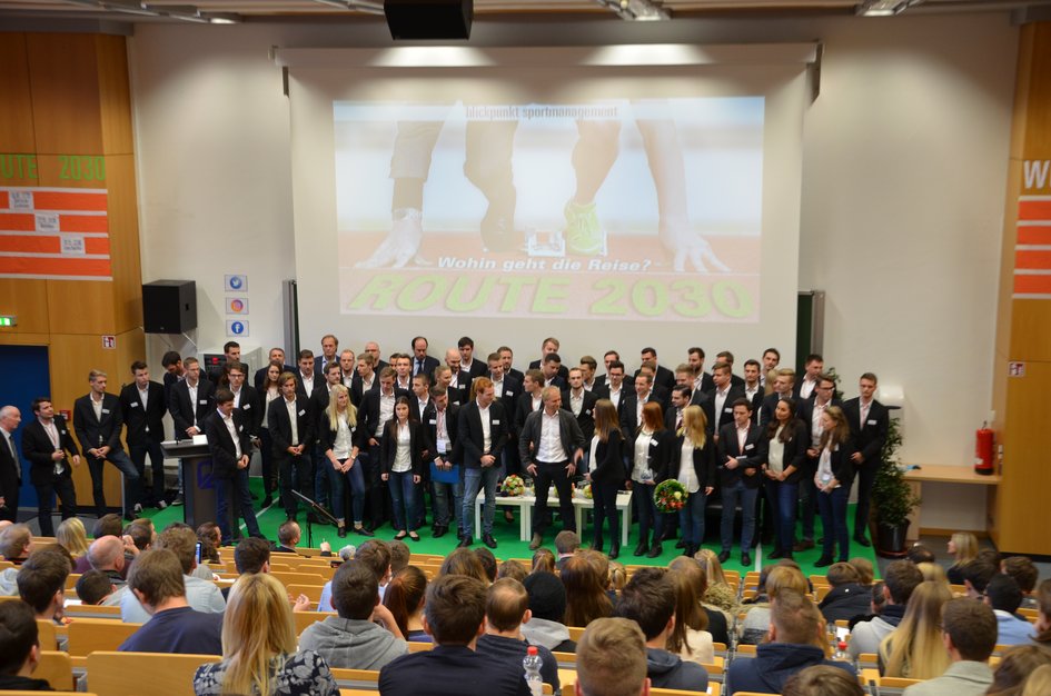 Die Mitglieder des Organisationskomitees stehen gesammelt auf der Bühne