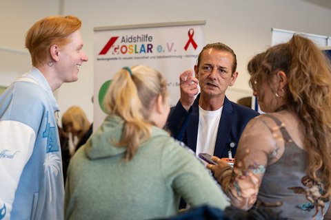 Ein Mitarbeiter eines Trägers im Gespräch mit einer Gruppe Studierender. (öffnet Vergrößerung des Bildes)
