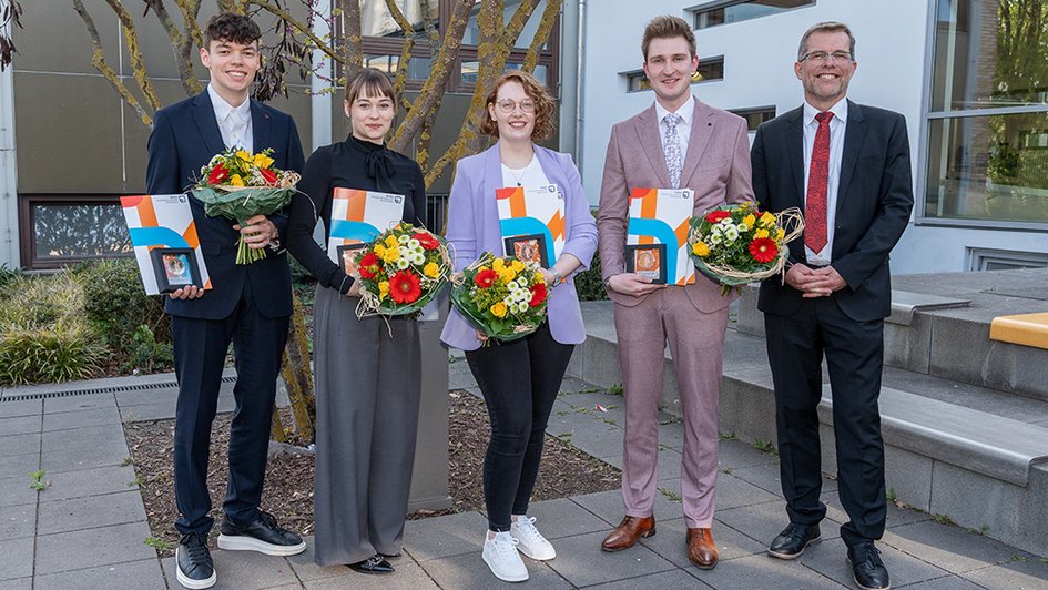 Gruppenbild mit den vier Preisträgerinnen und Preisträgern sowie dem Dekan. Die Abgebildeten lächeln in die Kamera. Die Ausgezeichneten halten ihre Awards und Blumensträuße.