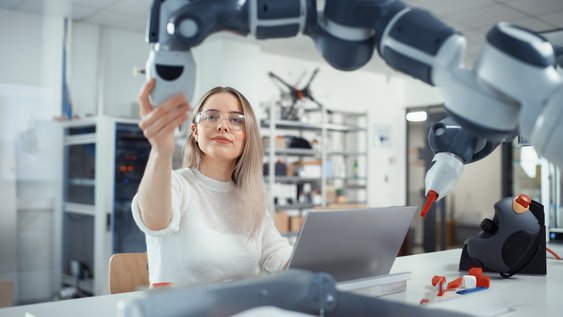 Eine Studentin untersucht eine Maschine und hält die Daten auf ihrem Laptop fest.