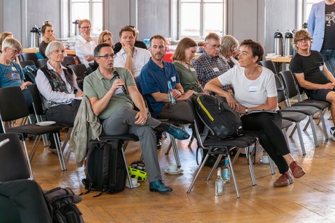 Foto ins Publikum, während ein Gast eine Frage stellt.