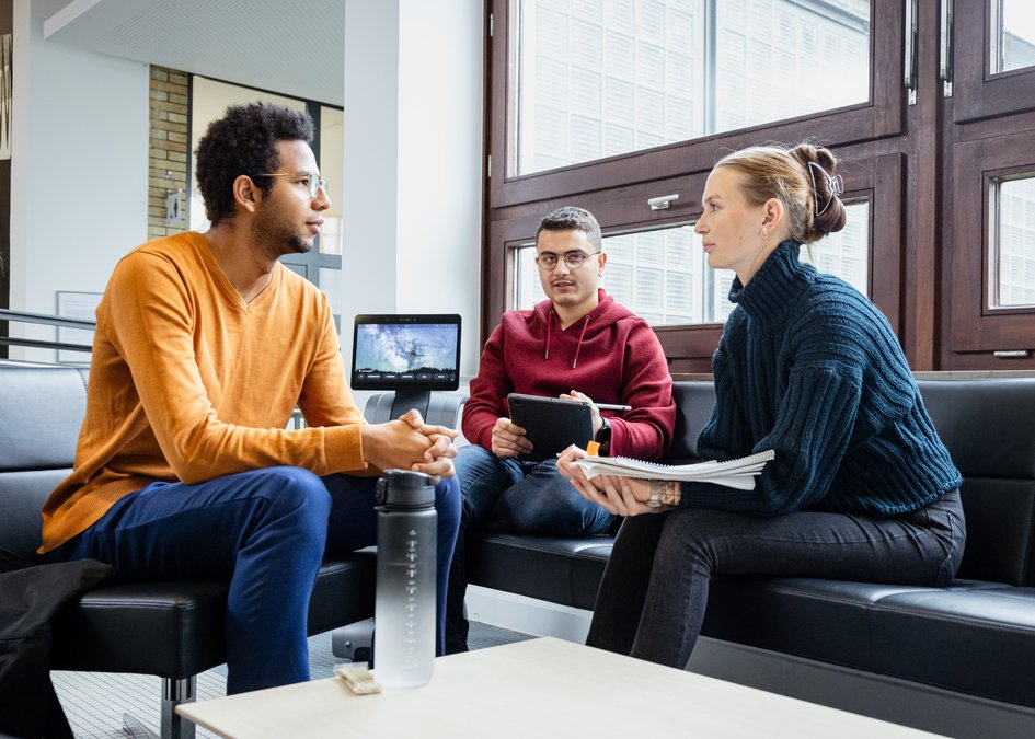 Studierende sitzen im Flur und unterhalten sich