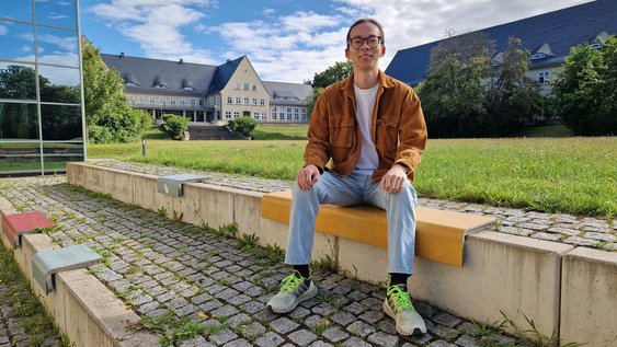 Student Linkai Yang sitzt draußen am Campus Am Exer in Wolfenbüttel