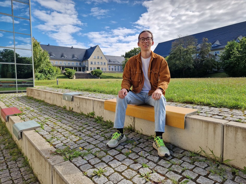 Student Linkai Yang sitzt draußen am Campus Am Exer in Wolfenbüttel