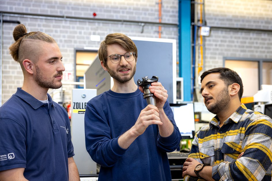 Drei Studierende der Ostfalia Hochschule arbeiten in der Maschinenbauhalle mit einem Werkstück. Am Campus Wolfenbüttel kann man unter anderem Maschinenbau studieren.