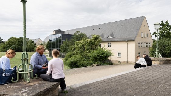 Studierende sitzen am Standort "Am Exer" auf einer Mauer. Der Standort gehört zum Campus Wolfenbüttel der Ostfalia Hochschule.