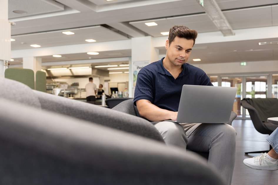 Ein Studierender arbeitet flexibel am Laptop. Am Campus Wolfsburg der Ostfalia Hochschule kann man Fahrzeugtechnik/Fahrzeugsystemtechnik (Online) studieren.
