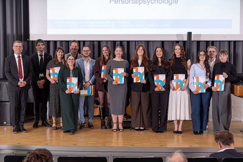 Gruppenbild der anwesenden Absolventinnen und Absolventen des Master-Studiengangs Recht, Personalmanagement und Personalpsychologie auf der Bühne. (öffnet Vergrößerung des Bildes)
