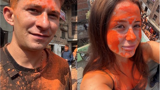 Niklas Wilms und Gökcen Sungur beim Neujahrfest in Nepal lächeln in die Kamera. Sie haben orangene Farbspritzer im Gesicht und auf der Oberbekleidung.
