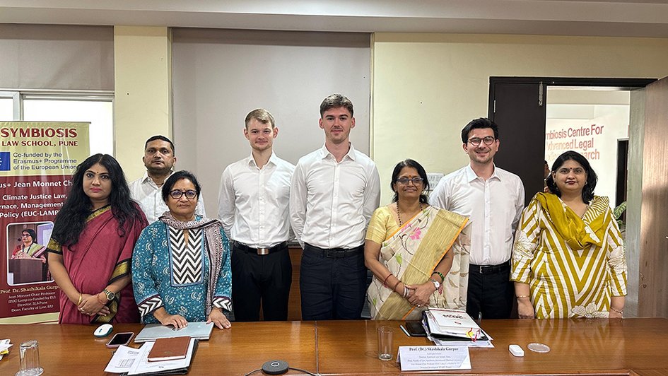 The BELS students are standing in a group of seven in a conference room at Symbiosis Law School, Pune, India.