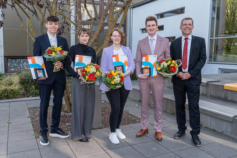 Gruppenbild mit den vier Preisträgerinnen und Preisträgern sowie dem Dekan. Die Abgebildeten lächeln in die Kamera. Die Ausgezeichneten halten ihre Awards und Blumensträuße.