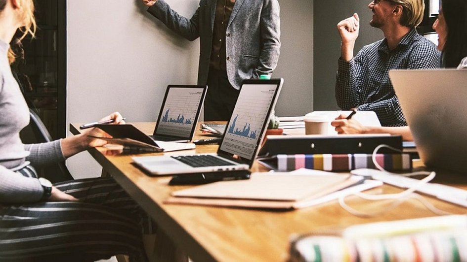 Dekorativ: Verkaufsteam in Meetingraum bei Präsentation mit Laptops, Diagrammen und Notizen, diskutiert Verkaufsstrategien.