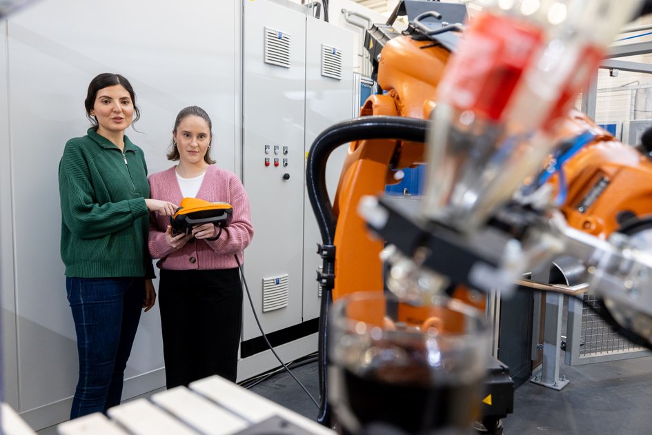 Zwei Studentinnen stehen im Labor vor einem Roboter