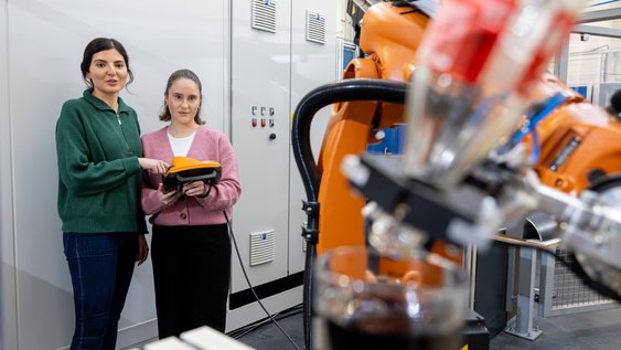 Zwei Studentinnen stehen im Labor vor einem Roboter