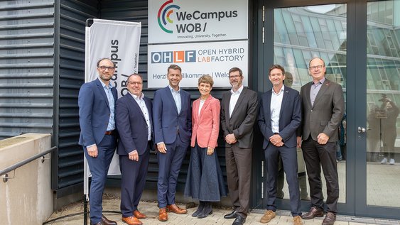 Bei der Namensverkündung am 11. Mai 2026 in Wolfsburg: Jens Hofschröer, Dezernent für Digitales und Wirtschaft Stadt Wolfsburg, Prof. Dr. Michael Thomas, Leiter Fraunhofer CCEM, Dennis Weilmann OB Stadt Wolfsburg, Prof. Dr. Angela Ittel, Präsidentin TU Braunschweig, Prof. Dr. Thomas Benda, Vizepräsident für Lehre, Studium und Weiterbildung, Ostfalia, Dr. Marko Gernuks, Volkswagen Group, 2. Vorsitzender OHLF e. V., Prof. Dr. Markus Henke, Vizepräsident Forschung und Internationales, TU Braunschweig.