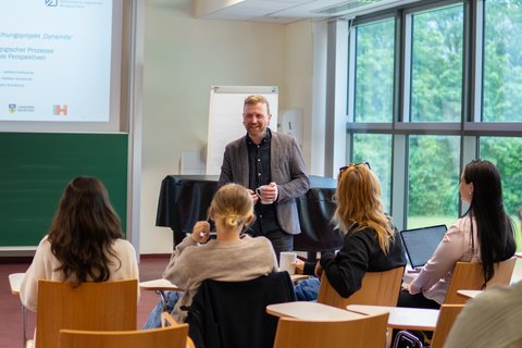 Prof. Dr. Timo Schreiner steht vor der vordersten Reihe des Vorlesungssaals und unterhält sich mit Studierenden aus der Fakultät Soziale Arbeit. (öffnet Vergrößerung des Bildes)