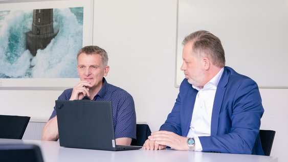 Zwei Professoren am Tisch und unterhalten sich über das Projekt.
