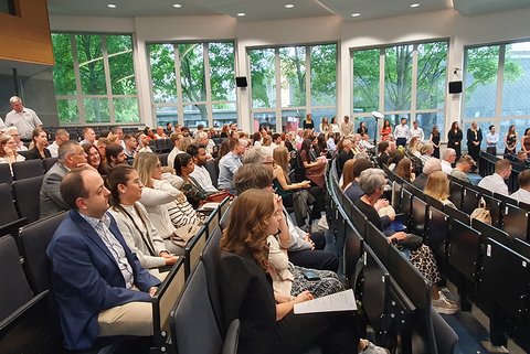 Die Personen im Auditorium der Aula folgen dem Programm der Abschlussfeier. (öffnet Vergrößerung des Bildes)