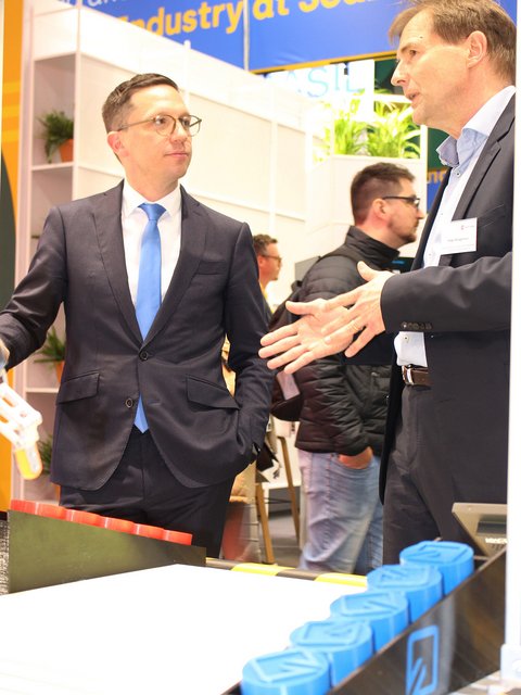 Minister Falko Mohrs in conversation with researchers from Ostfalia University of Applied Sciences and Arts at Hannover Messe 2026. (opens enlarged image)