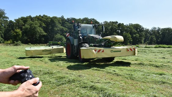 Pressefoto (Adrian Grimm): Das Symbolbild zeigt einen Traktor mit Front- und Heckmähwerk sowie einen Controller. An verschiedenen Möglichkeiten und Rahmenbedingungen der externen Steuerung als Schritt zur Automatisierung landwirtschaftlicher Maschinen und Prozesse wird im Projekt GESAL gearbeitet.