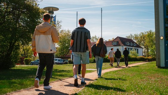 5 Studierende gehen hintereinander auf das Gebäude A am Campus Suderburg zu.