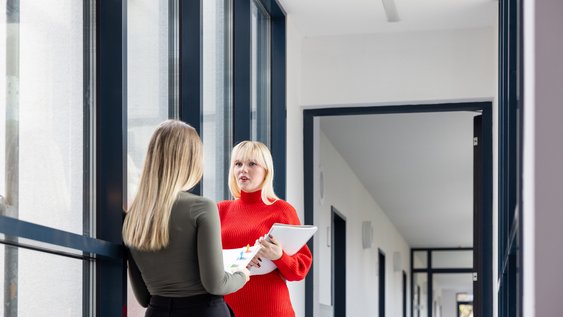 Zwei Studentinnen der Ostfalia Hochschule sprechen am Campus Wolfenbüttel miteinander.