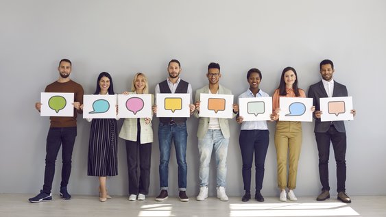 Group of people holding white sheets of paper with empty colored speech bubbles on them.
