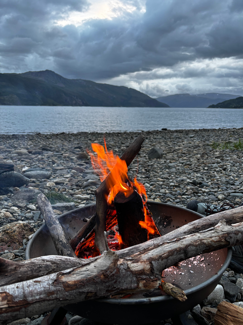 Nahaufnahme eines Lagerfeuers mit Blick auf die Fjorde (öffnet Vergrößerung des Bildes)