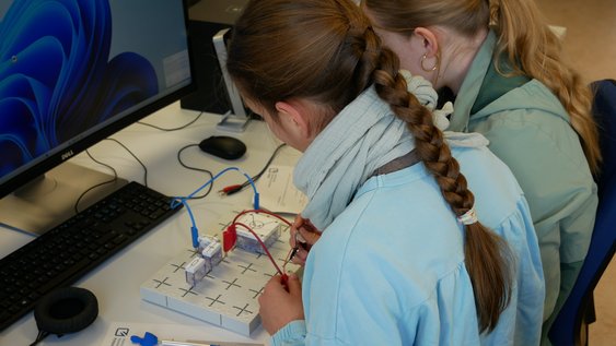 Zwei Schülerinnen stecken Schalter zusammen, um einen Audioverstärker zu bauen. 