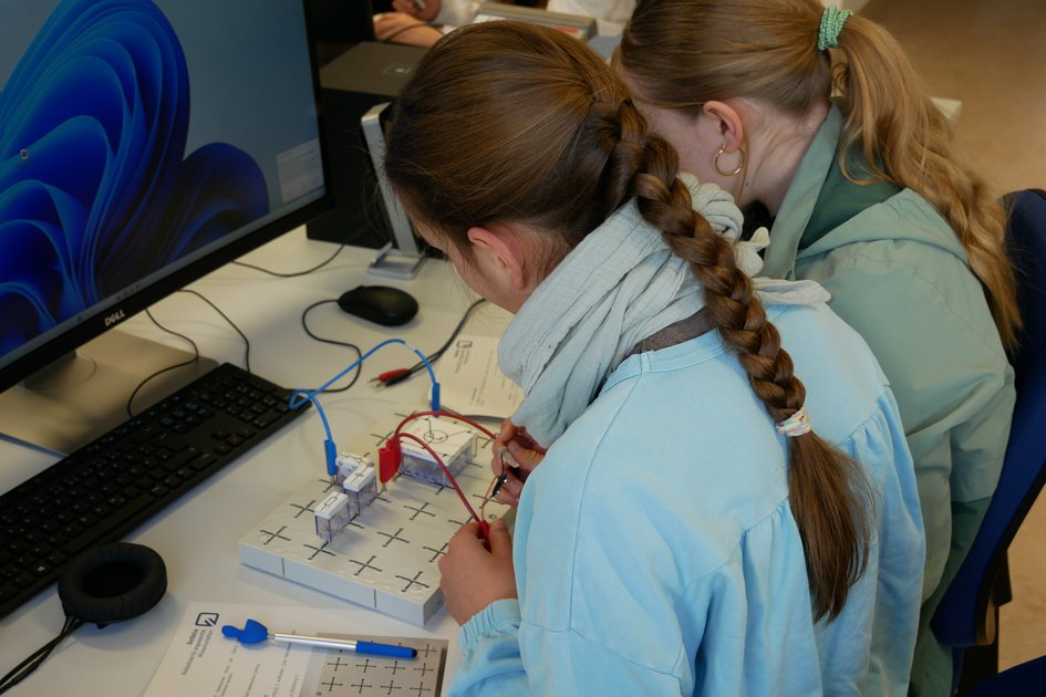 Zwei Schülerinnen stecken Schalter zusammen, um einen Audioverstärker zu bauen. (öffnet Vergrößerung des Bildes)