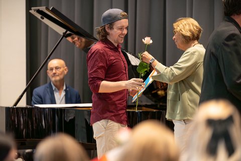 Dekanin Prof. Dr. Sandra Verena Müller reicht einem Absolventen auf der Bühne eine Rose. (öffnet Vergrößerung des Bildes)