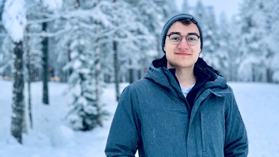 Absolvent Felix steht in einer Schneelandschaft von Finnland