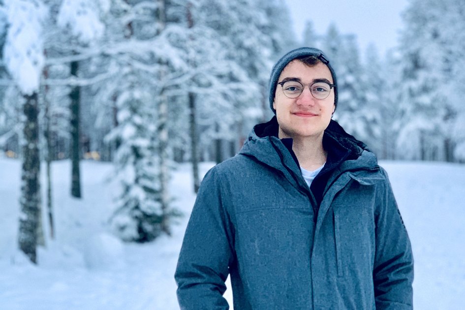 Absolvent Felix steht in einer Schneelandschaft von Finnland