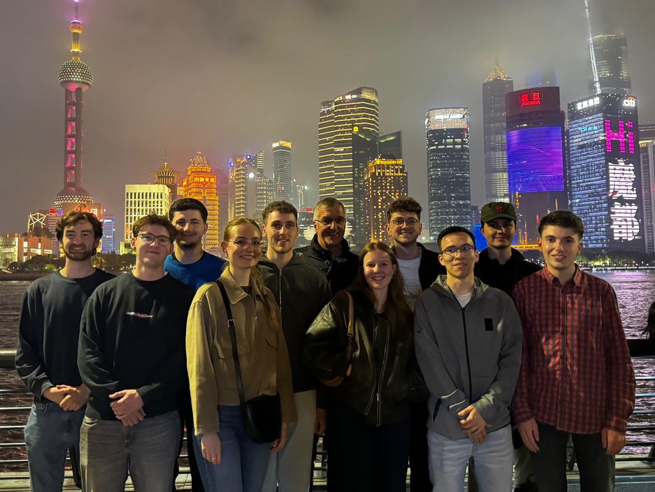 Eine Gruppe Studierender steht vor der Skyline von Shanghai