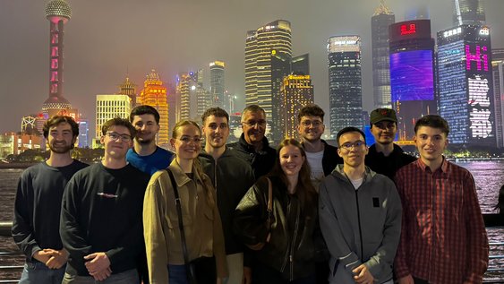 Eine Gruppe Studierender steht vor der Skyline von Shanghai