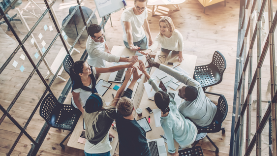 Acht junge Menschen, die in einem Workspace im Team arbeiten. 