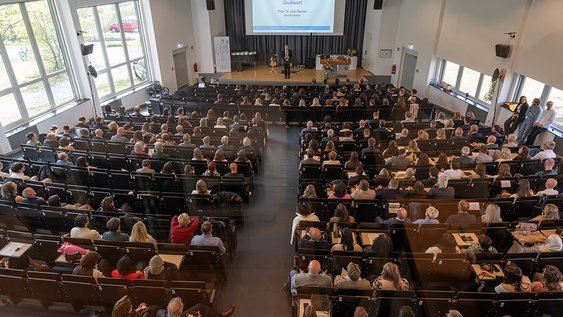 Blick von hinten auf die fast vollbesetzte Aula aus der Vogelperspektive.