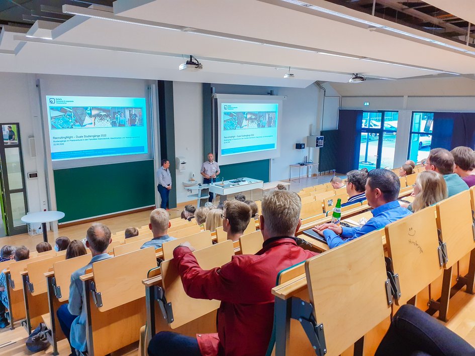 Verschiedene Personen sitzen im Hörsaal und hören bei der RecruitingNight zu