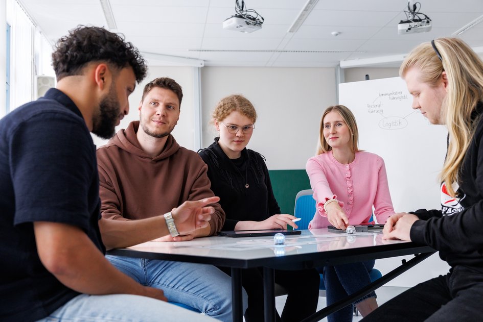Studierende sitzen diskutierend an einem Tisch.