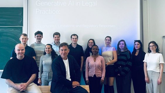Gruppenbild der Teilnehmerinnen und Teilnehmer des LegalTech-Blockseminars zusammen mit Prof. Dr. Stancke (2. v l. in Reihe 1), auf der Beamerfläche hinter den Personen ist eine Präsentation mit dem Thema "Generative AI in Legal Practice" zu sehen.