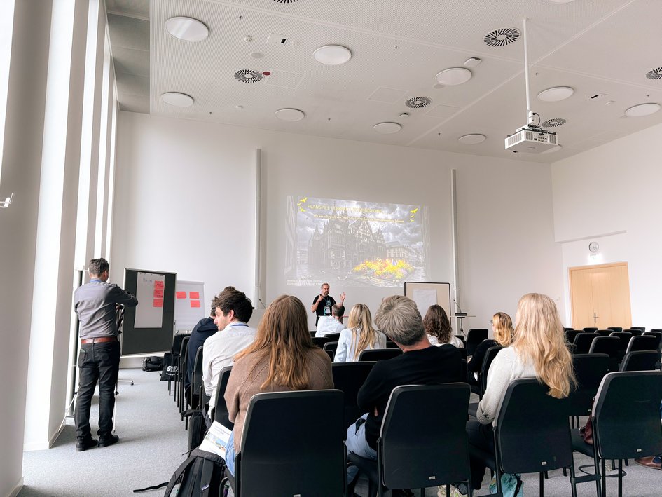Prof. Dr.-Ing. Jan Büchsenschuß und Student Hendrik Pergande auf der Bühne des Workshops " Verwaltungspingpong. Wie man ein Smart City Projekt erfolgreich durch eine Kommunalverwaltung bekommt"